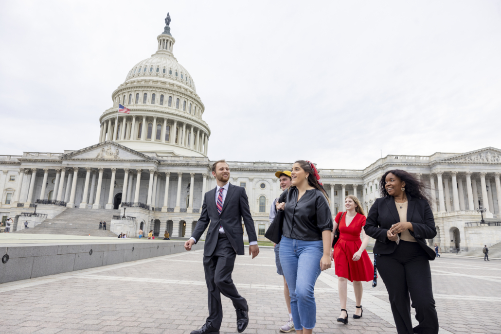 (L-R) Undergraduate students Logan Williamson, Jacob David, Emma Brandwein, Caroline Schneider and De’Omini Daniely walk past the U.S. Capitol building.