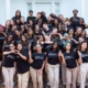 A large group of students wearing black t-shirts smiling for the camera