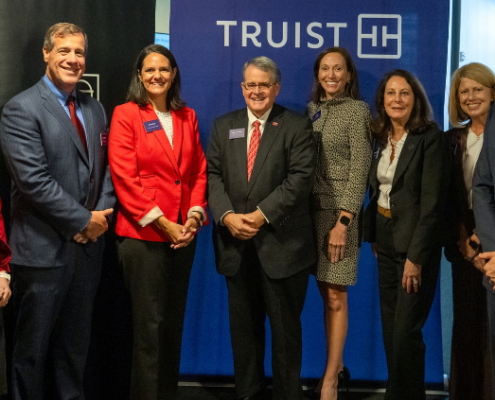 A group of people stand smiling in front of a Truist sign.