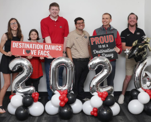 Six Destination Dawgs participants pose with celebratory balloons denoting their graduation in 2026.