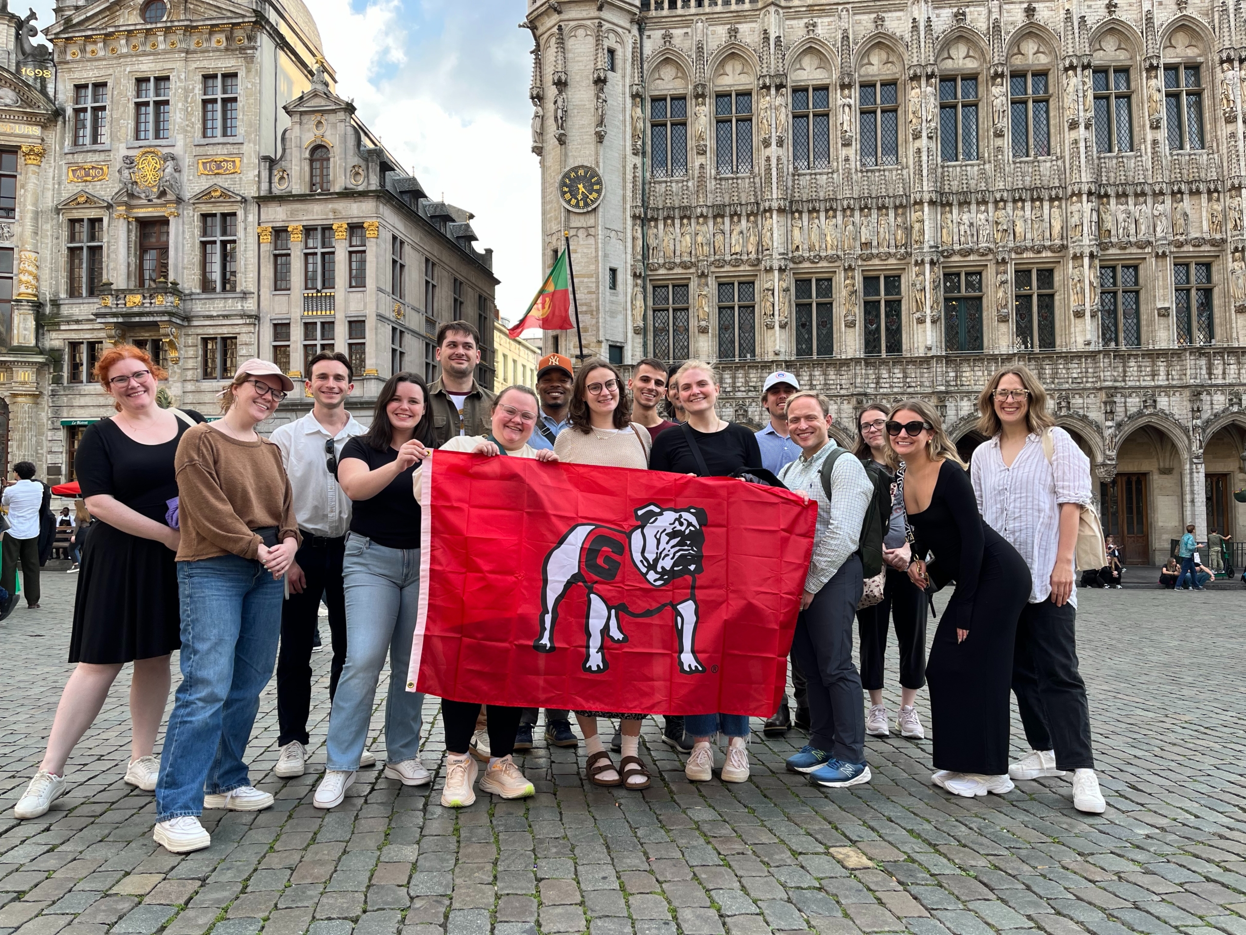 Students pose in brussels with a UGA themed flag