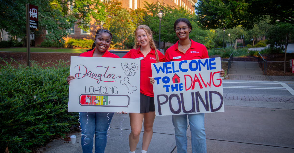 Photo of three UGA students with rally signs
