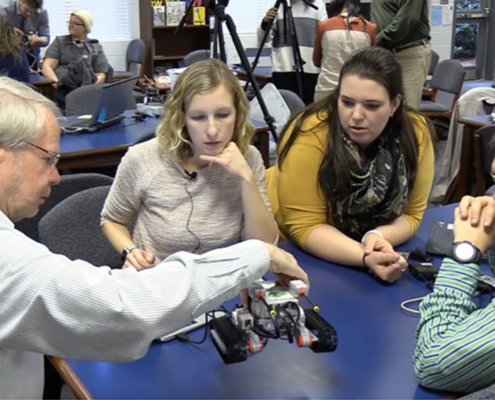 Roger Hill (left) demonstrates how robotics can be incorporated into the classroom for a group of teachers.