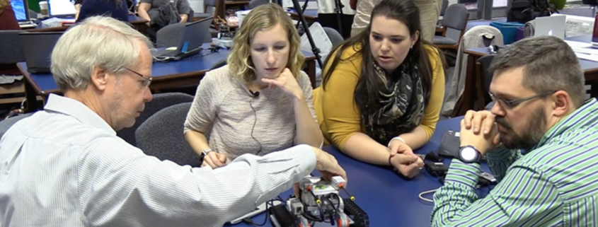 Roger Hill (left) demonstrates how robotics can be incorporated into the classroom for a group of teachers.