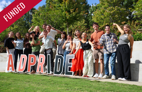 "Funded" banner overlaid on a photo of a group of smiling students outdoors with "AD PRIDE" letters.