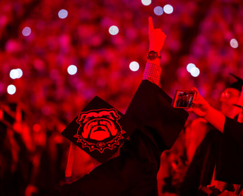 Students are illuminated in red light during Spring 2022 Undergraduate Commencement at Sanford Stadium. (credit: Chamberlain Smith)