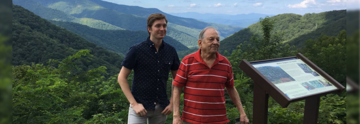 Phillip Gregory, left, stands with his uncle, Bruce Gregory, by a sign off the Blue Ridge Parkway, the design and construction of which Bruce contributed to in the 1960s.