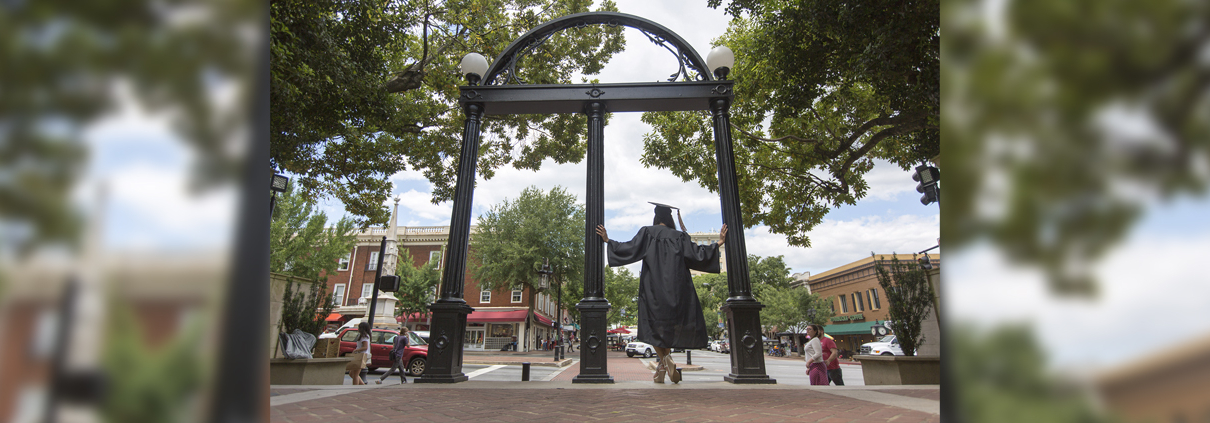 A student takes cap and gown photos at the Arch.