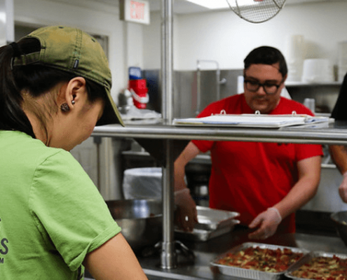 Three Campus Kitchen volunteers serve meals.