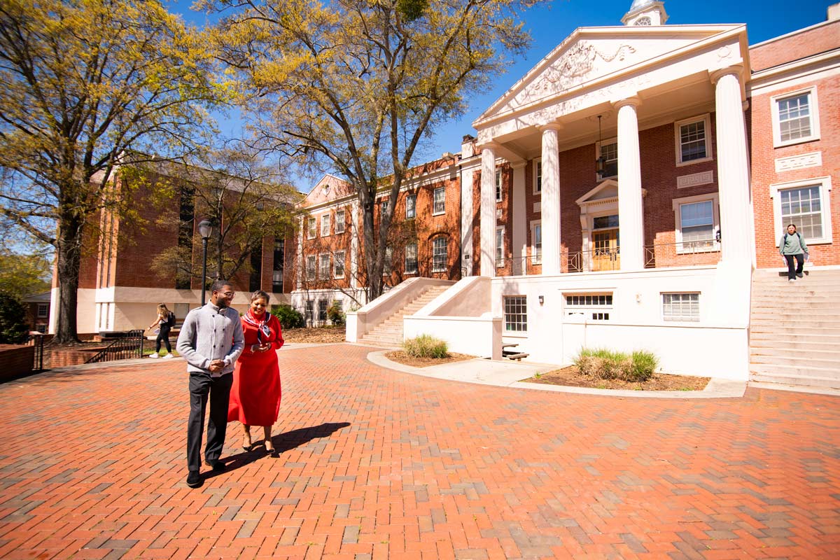 Neicy Wells walks with her son in front of Park Hall.