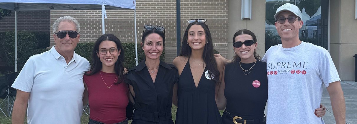 A family of six smiles for a photo outside.