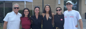 A family of six smiles for a photo outside.