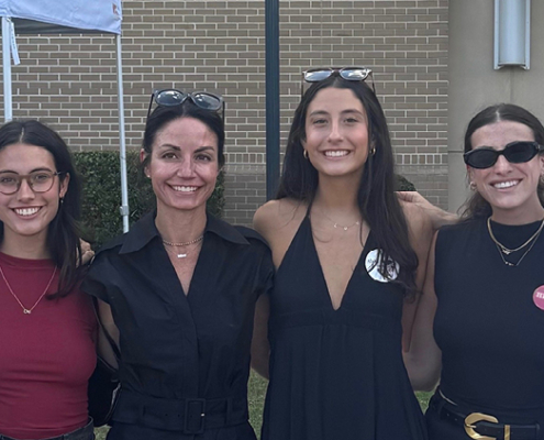 A family of six smiles for a photo outside.