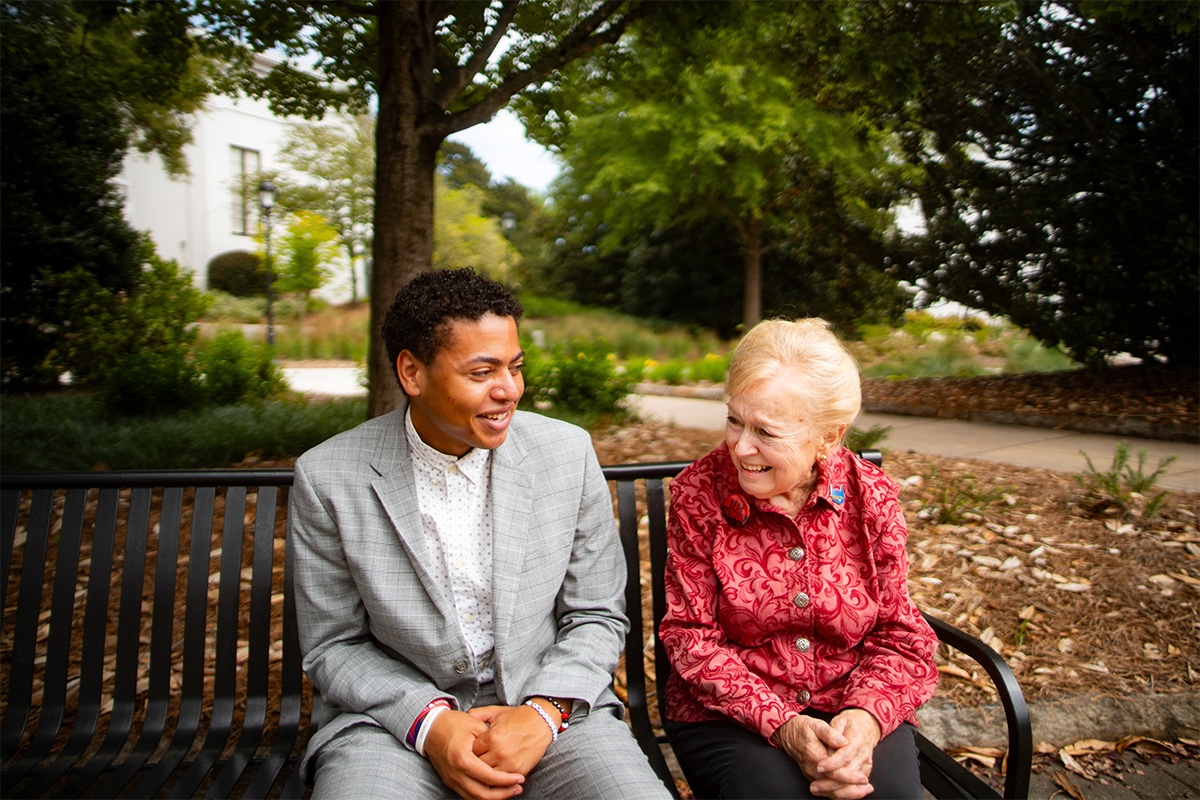 Donor Kathy Hoard and recipient Mason Howard talk together on a bench on campus.