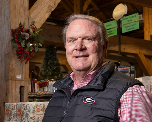 A smiling man stands in a rustic storefront.