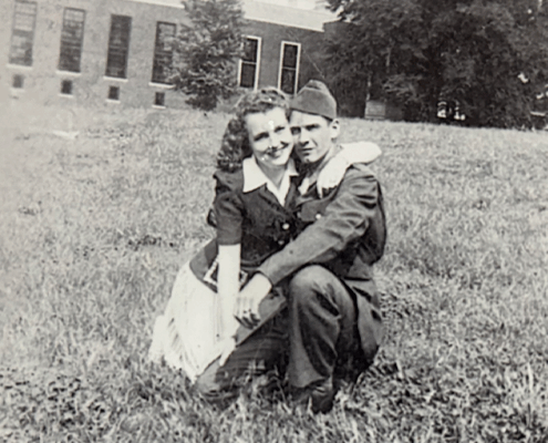 A man and woman pose on a grassy field in a vintage photograph.