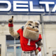 UGA mascot, Hairy Dawg, poses in front of a Delta sign.