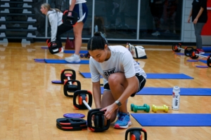 A female student adjusts weights at a weightlifting course