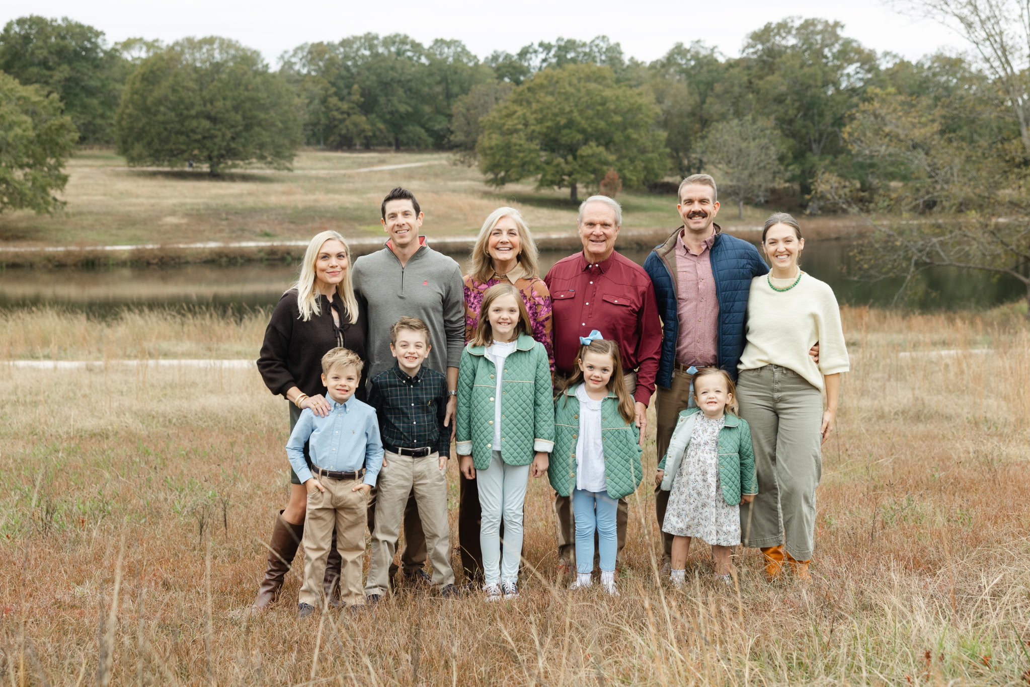 A group of eleven family members stand smiling in a field.
